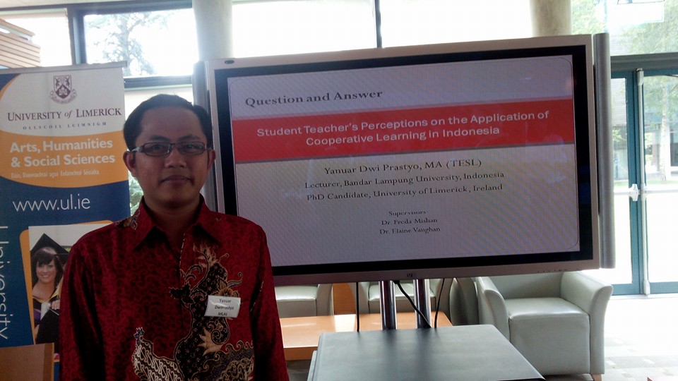 Yanuar stands beside a presentation slide featuring his thesis - "student Teacher's perceptions on the application of co-operative learning in indonesia"