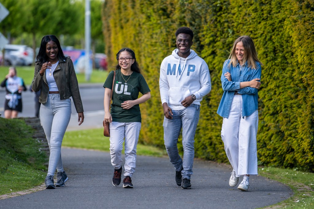 A diverse group of students walking together on campus laughing