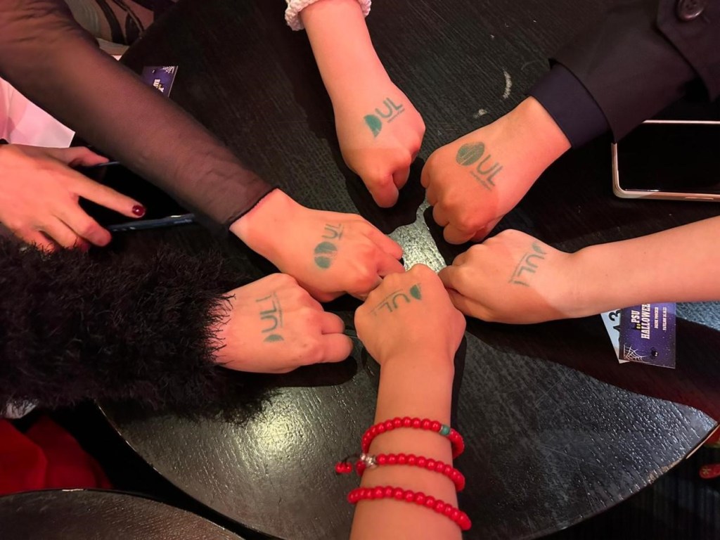 A group of hands with a UL stamp on their hands going to a ul student event