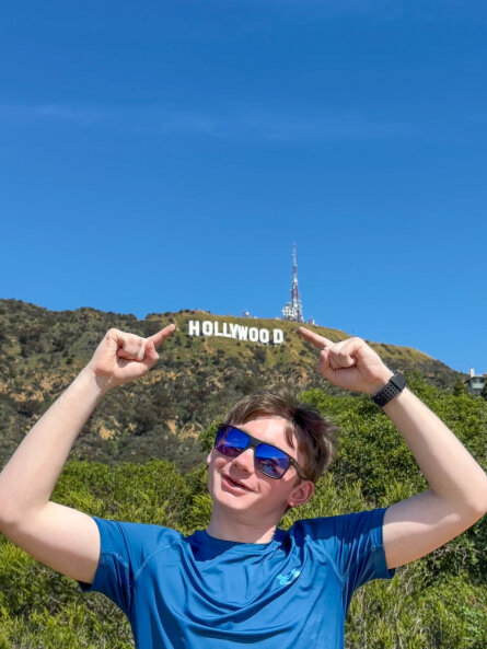 Daniel standing in front of the iconic Hollywood Sign in Los Angeles, California.