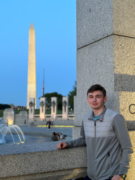 Daniel standing at the World War 2 memorial in front of the Washington Monument.