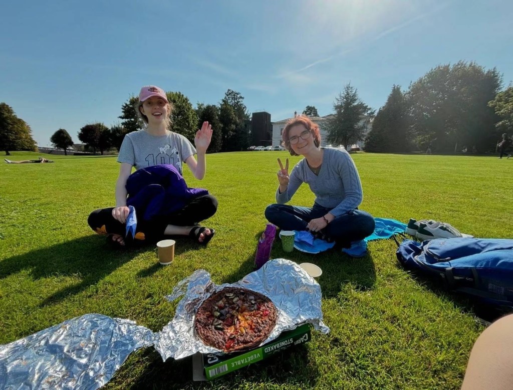 Niri's friends eating on the lawn in front of the Living Bridge
