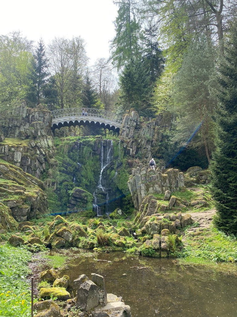 A beautiful view of a bridge over a moss covered waterfall