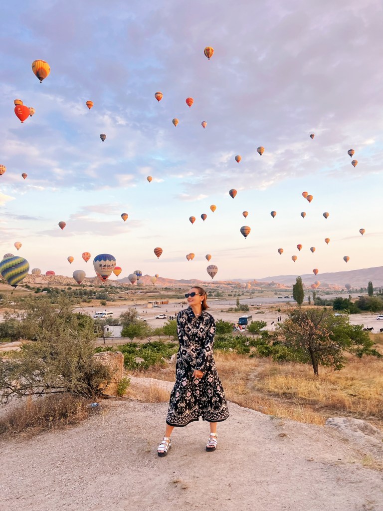 Yaqian in front of a lot of hot air balloons in flight