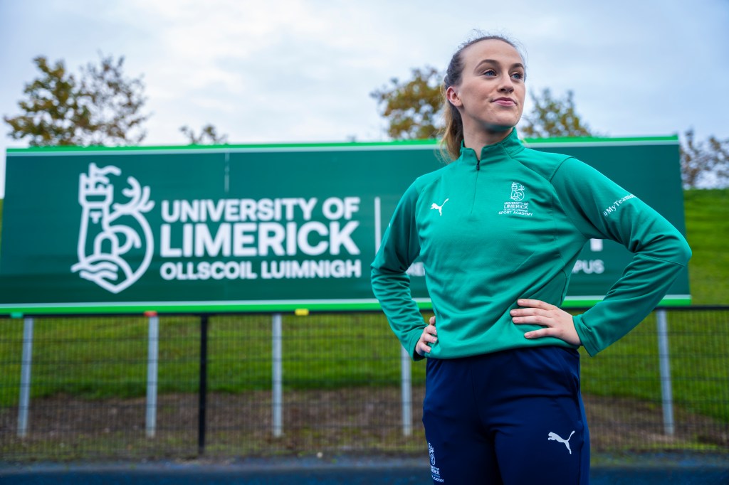 A student runner standing in front of the UL sign on the UL Sports track
