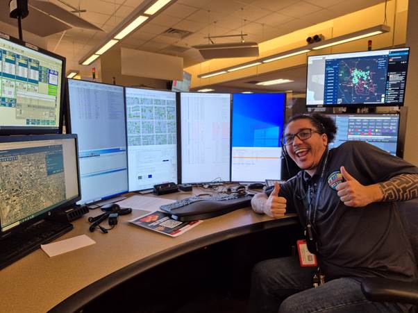 Julian smiling and giving the thumbs up in front of his work screens 