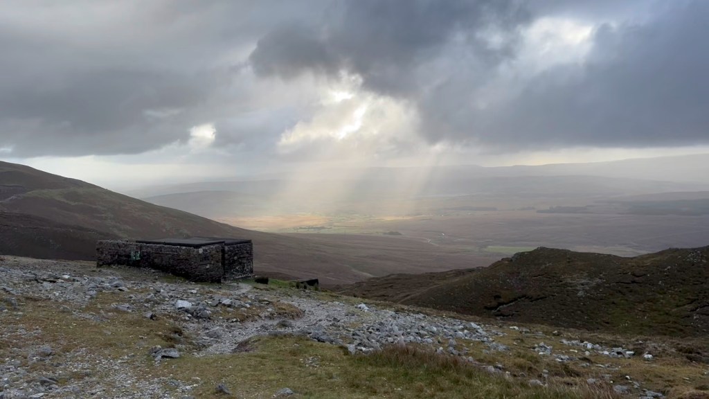 A view from the top of the Mountain, with sunlight peeking from a cloudy sky