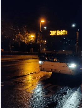 A nighttime shot of the 300 bus coming to a bus stop