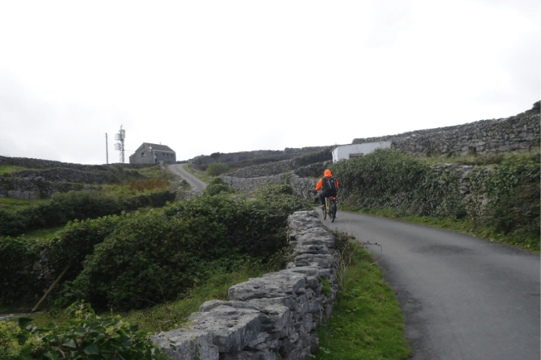 A person cycling on narrow road on the Island of Inisheer