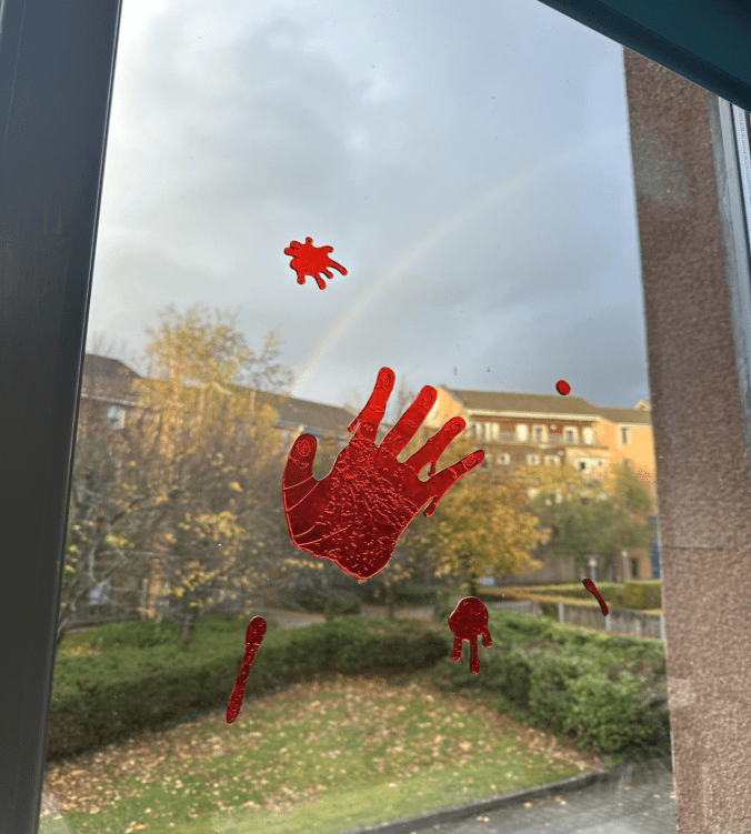 Halloween decorations of a bloody handprint on a window