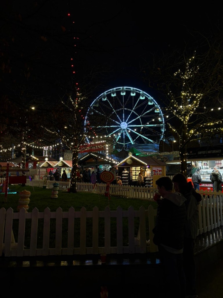 Image of a Christmas market at night with a Ferris wheel.