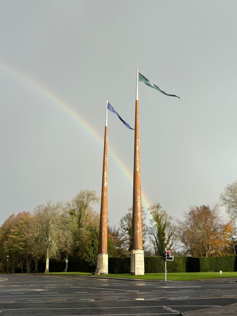 Image of a rainbow behind the flagpoles at ULs entrance.