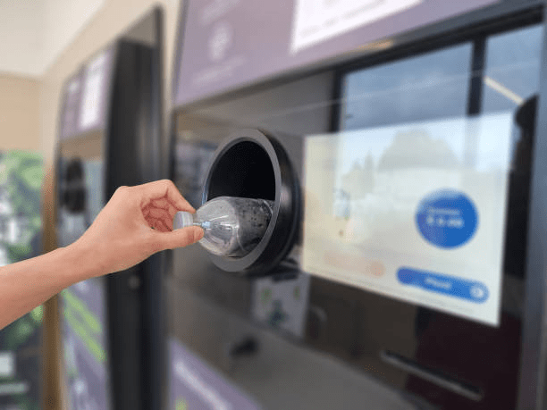 Image showing someone returning a plastic bottle into a deposit return scheme machine.