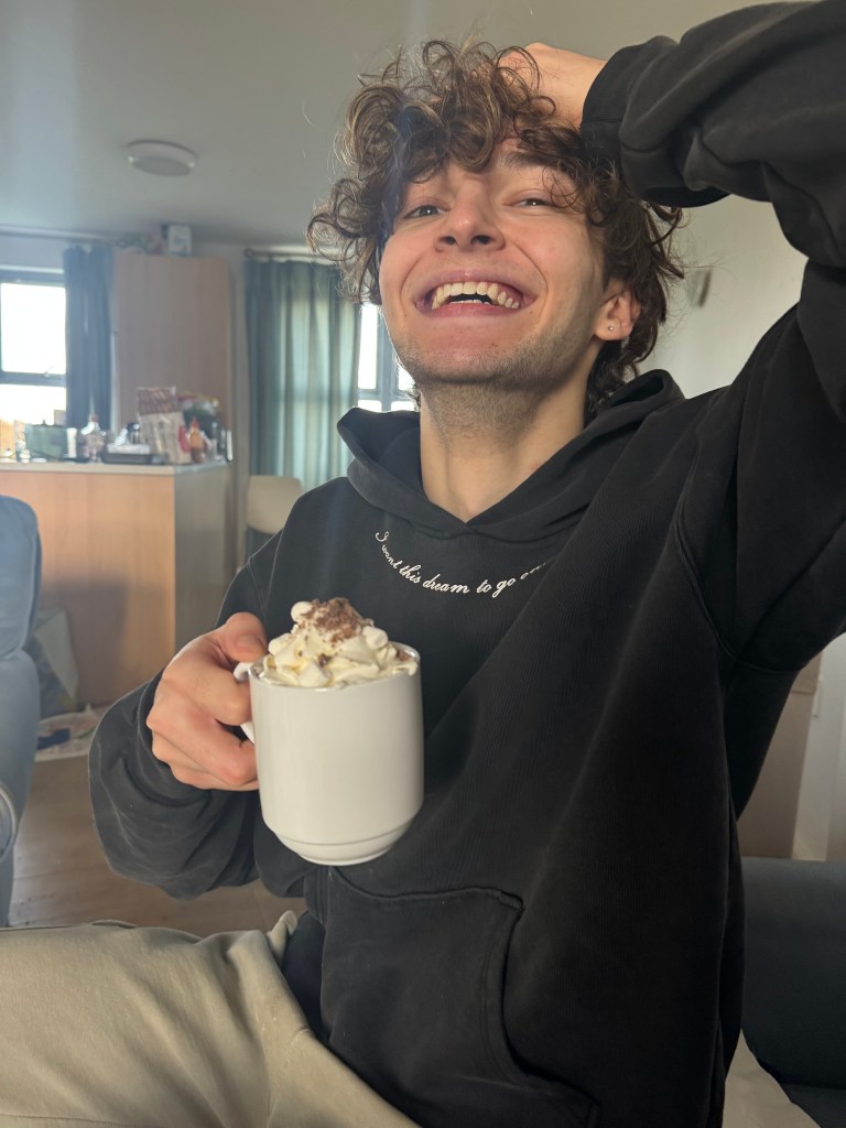 Image of Maddox enjoying a hot chocolate with whipped cream and marshmallows.
