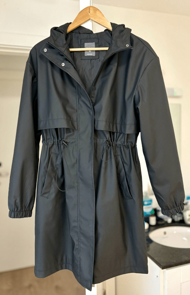 Image of Katies long black rain coat hanging up.