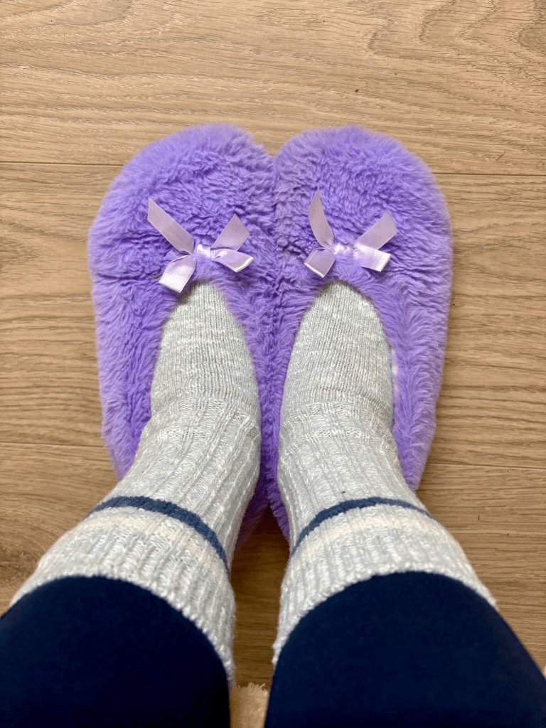 Image of Katies cozy purple slippers on her feet.