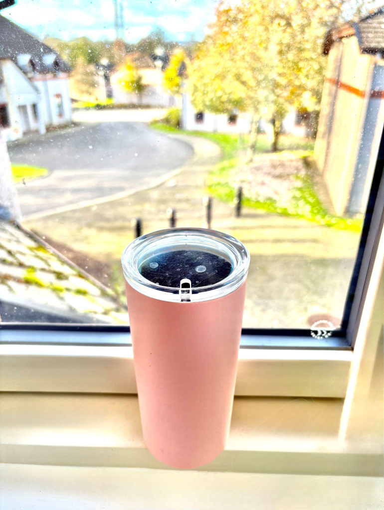 Image of Katies Pink to-go cup placed on her windowsill. 